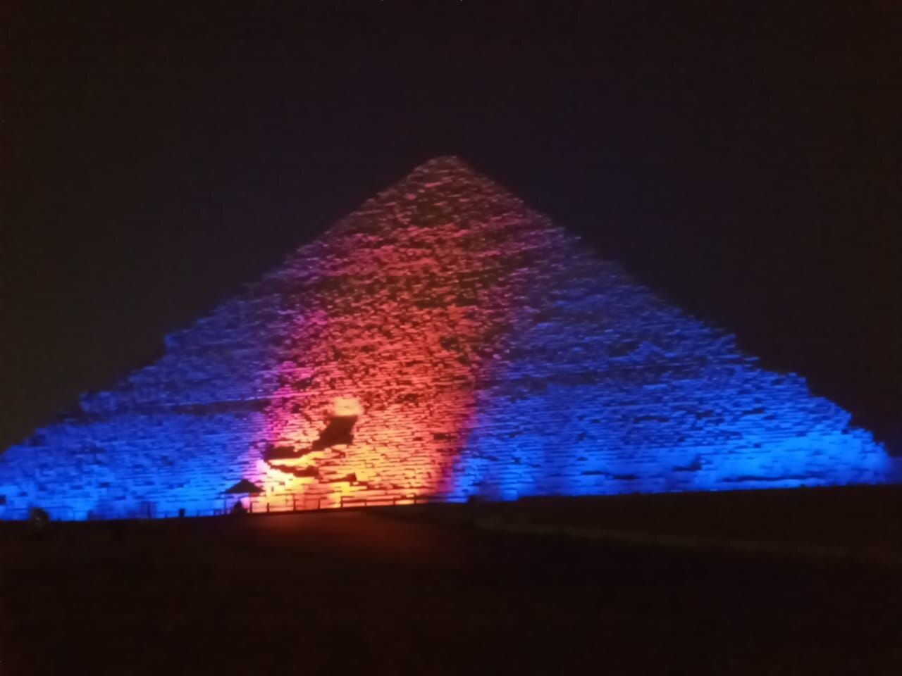 The pyramid of Cheops in Egypt lit up with blue and orange light